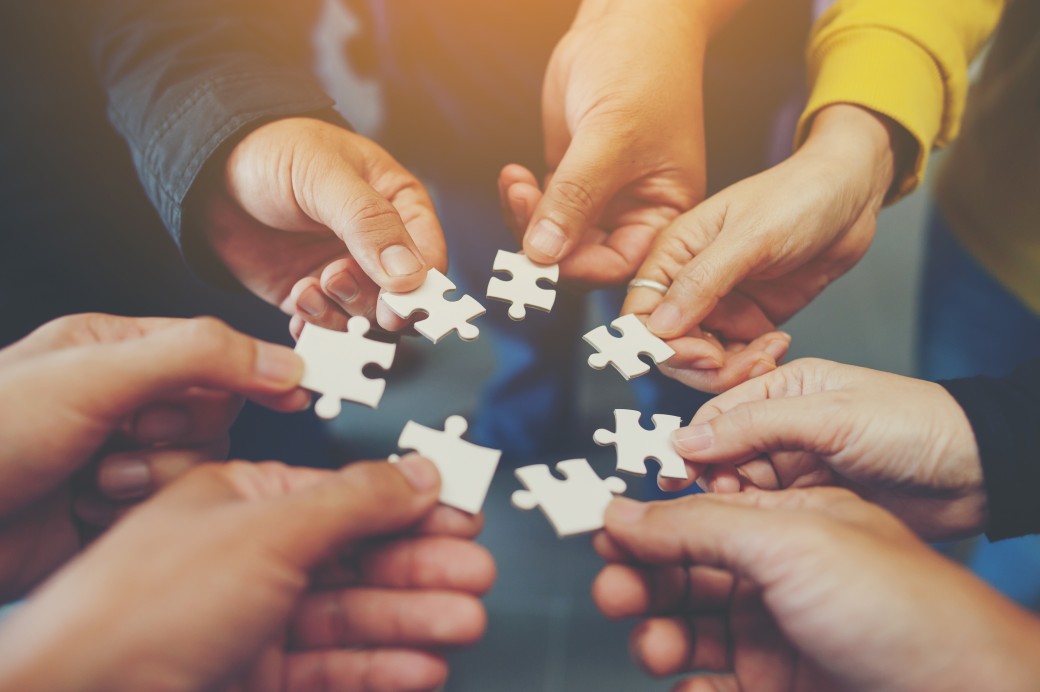 Kreis aus Händen halten Puzzleteile in der Mitte